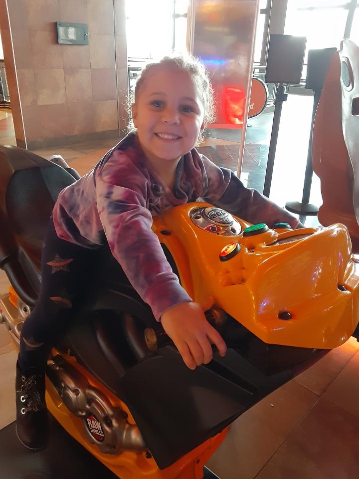 Nala plays, smiling, on orange toy vehicle