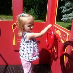 Child playing with playground firetruck wheel